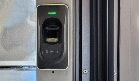 Fingerprint and card access reader controlling entry at a business door
