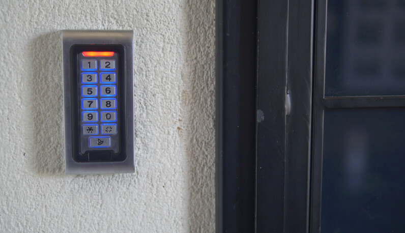 Keypad access control reader mounted beside a commercial glass door