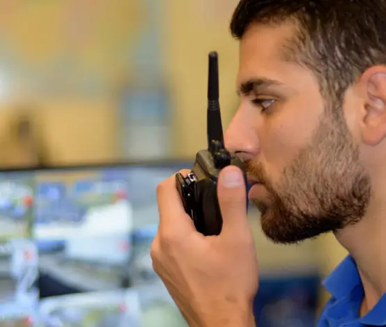 Security team member on a two-way radio responding to an alarm while watching camera feeds Security team member on a two-way radio responding to an alarm while watching camera feeds