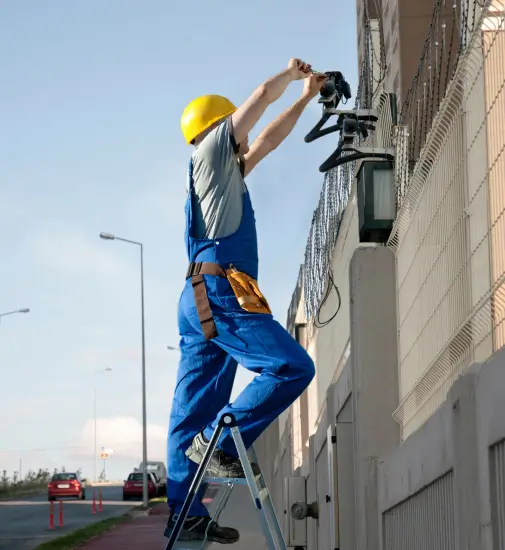 Technician installing commercial security cameras on a Dallas building