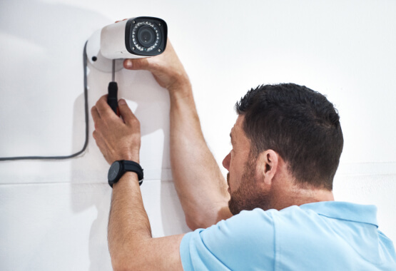 Technician installing a security camera for a Carrollton business